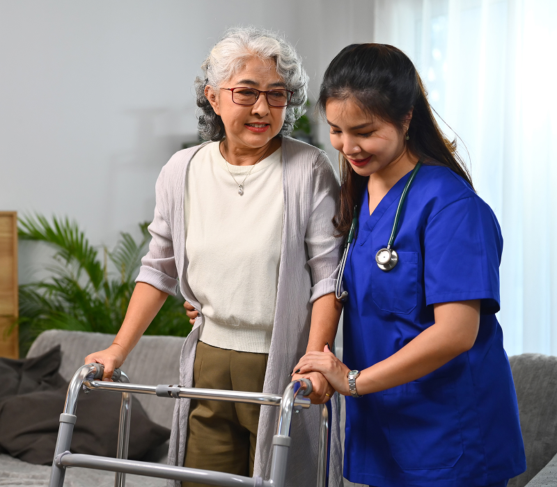 female nurse helping senior woman walking her home with walker